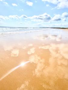 a beach with a reflection of clouds in the sand at #MirrorSands in Blythe
