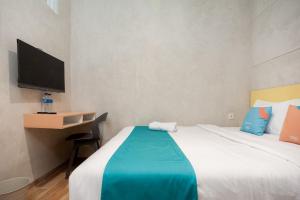 a bedroom with a bed and a desk and a tv at Sans Pasar Lama Tangerang in Tangerang +23 photos