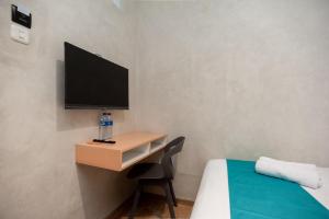 a bedroom with a desk with a tv and a bed at Sans Pasar Lama Tangerang in Tangerang