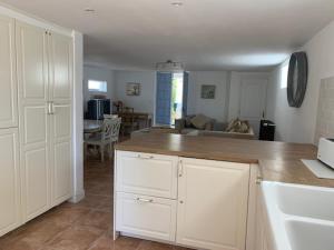 a kitchen with white cabinets and a living room at La Cour des Cloches in Mainxe