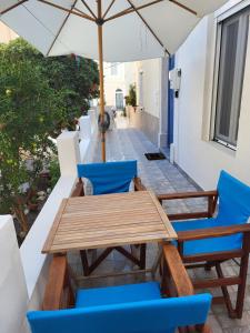 einen Holztisch und Stühle auf einem Balkon mit Sonnenschirm in der Unterkunft Lion's House in Kalymnos