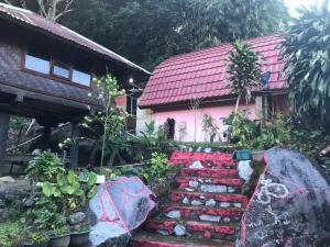 a garden in front of a pink house at Bungalow Paer Doe in Sembalunbumbung