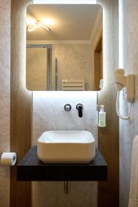 uma casa de banho com um lavatório e um espelho em Hotel Eden em Rimnicu Sarat