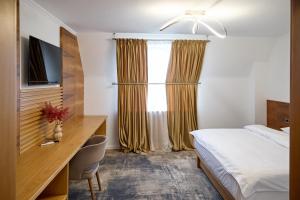 Una habitación de hotel con una cama, un escritorio y una ventana. en Motel Eden, en Rîmnicu Sărat