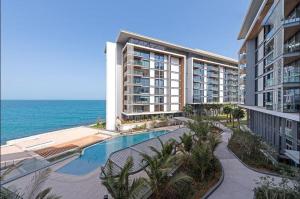 a large building with a swimming pool next to the ocean at Nasma Luxury Stays - Gorgeous Waterfront Apt With Incredible Sea Views in Dubai