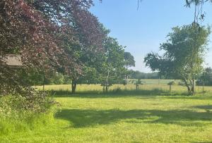 un campo de césped con árboles en el fondo en Cottage 7 mins from Henley with gated parking en Henley on Thames