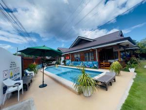 a house with a swimming pool and an umbrella at Dolce Vita Resort in Moalboal