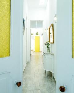 un couloir avec des murs blancs et une porte jaune dans l'établissement Casa Ella, à Olhão