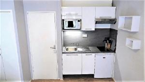 a small kitchen with white cabinets and a microwave at Charmant T2, hypercentre, calme, terrasse, parking in Luchon +44 photos