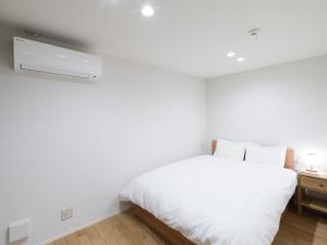 1 dormitorio con cama blanca y pared blanca en Rakuten STAY HOUSE x WILL STYLE Hagi Nishitamachi en Hagi