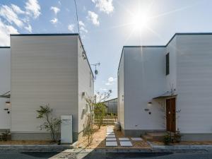 zwei weiße Gebäude mit der Sonne zwischen ihnen in der Unterkunft Rakuten STAY HOUSE x WILL STYLE Hagi Nishitamachi in Hagi