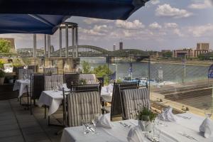 a restaurant with tables and chairs with a view of a river at Maritim Hotel Köln in Cologne