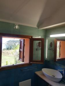 un bagno con lavandino, specchio e finestra di Accu is prezzus I 30mt dal mare a Villasimius