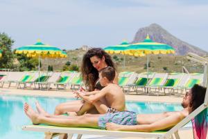 Eine Frau und ein Kind sitzen auf einem Strandkorb im Pool in der Unterkunft Villa Zina Family Resort in Custonaci