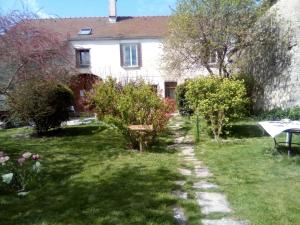 a garden in front of a white house at La Grille Fleurie, chambre d'hôte chez l'habitant in Arthonnay