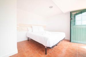 a white bed in a room with a green door at Casa A Bicuda in Ferrol