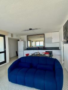 un sofá azul en una sala de estar con cocina en Le Mousse, P2 cosy avec une magnifique vue mer, parking, en La Grande-Motte
