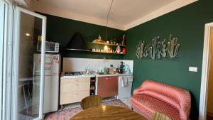 a kitchen with green walls and a table and a refrigerator at BnB Tripoli in Turin