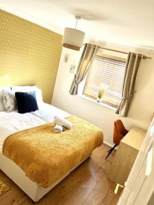 a bedroom with a bed with a yellow blanket and a window at Campbell Park apartment with a balcony and free parking in Milton Keynes