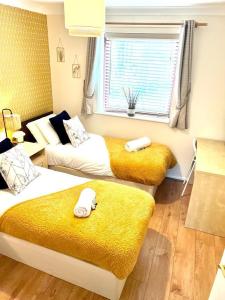 a bedroom with two beds with yellow blankets and a window at Campbell Park apartment with a balcony and free parking in Milton Keynes