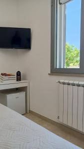ein Schlafzimmer mit einem Bett und einem TV an der Wand in der Unterkunft Smilax - Hydruntum Holiday Rooms in Otranto