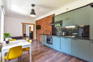 a kitchen with blue cabinets and a table with yellow chairs at VILLA KURLAND in Ventspils