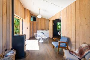 a living room with wood paneling and a table and chairs at The Urban Tramping Hut in Rotorua