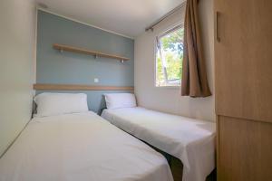 two beds in a small room with a window at Camping La Masia in Blanes