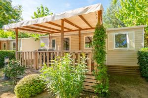 Casa con porche de madera con dosel en Camping La Masia en Blanes