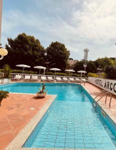 a large swimming pool with chairs and umbrellas at Hotel Arcobaleno in Celle Ligure
