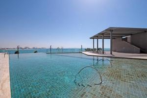 a large swimming pool with a clear blue water at Nasma Luxury Stays - Gorgeous Waterfront Apt With Incredible Sea Views in Dubai