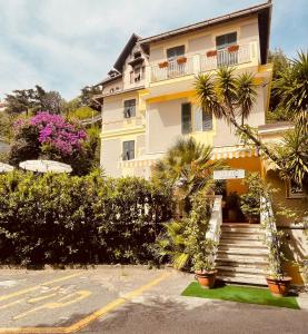 un edificio amarillo con escaleras y plantas delante en Hotel Arcobaleno, en Celle Ligure