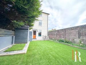 a backyard with a large yard with a brick wall at Fisherman's Cottage - Harwich Breaks - BRAND NEW - long stays available great prices - get in touch for all bookings - cottage in harwich - beach stay in Harwich