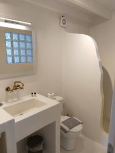 a white bathroom with a sink and a toilet at Oniropagida Nisyros apartment #1 in Nikiá