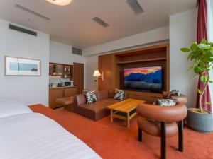 um quarto de hotel com uma cama, um sofá e uma televisão em Rakuten STAY Atami em Atami