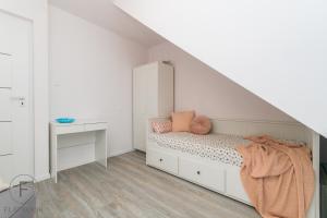 a white bedroom with a bed and a staircase at Flatbook Apartamenty - Mikoszewo Wczasowa I in Mikoszewo