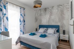 a bedroom with a blue bed with two towels on it at Apartamenty Pod Cisem Lux in Kudowa-Zdrój