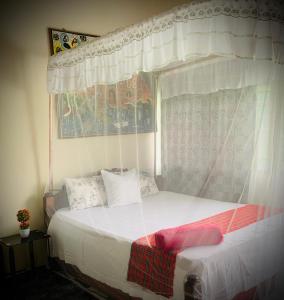 Jambo Diani 1-bedroom apartment close to the beach في شاطئ دياني: غرفة نوم بسرير مع مظلة