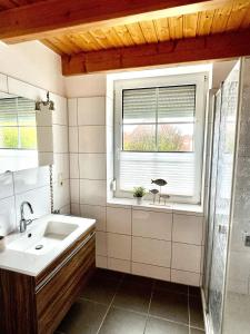 ein Bad mit einem Waschbecken und einem Fenster in der Unterkunft Nordseeferien Nessmersiel in Neßmersiel