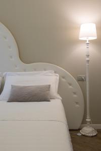 a white bed with a white headboard and a lamp at BeB San Lorenzo in Bergamo