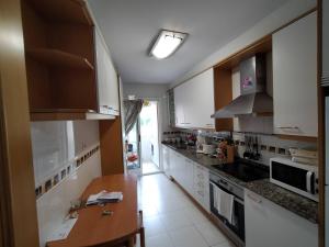 a kitchen with white cabinets and a wooden table at Apartamento en Sada in Santa María
