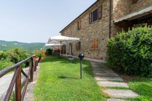 a building with a table and an umbrella next to it at Pugnano Alto - appartamento Tabacco in Lisciano Niccone