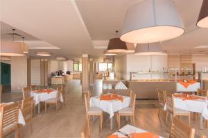 a restaurant with white tables and chairs and a kitchen at Hotel Pomorie Sun in Sunny Beach