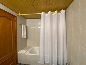 a bathroom with a white shower curtain and a tub at Hotel Rural Cal Amadeu in Vilanova de Escornalbou