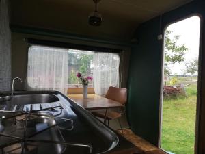 a kitchen with a sink and a table and a window at Cute little caravan for 2 in old orchard in Hem