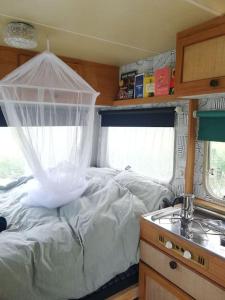 a bedroom with a white bed with a window at Cute little caravan for 2 in old orchard in Hem