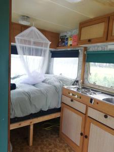 a bedroom with a bed and a sink in a rv at Cute little caravan for 2 in old orchard in Hem
