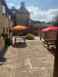 um pátio com duas mesas de piquenique e um guarda-chuva em The Queens Head Inn em Milton Ernest