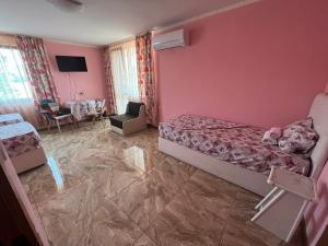 um quarto com paredes cor-de-rosa, uma cama e uma mesa em Daniel Guest House em Nesebar