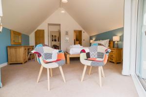 a bedroom with two chairs and a bed at Trewhiddle Retreat V10 by Together Travel - Luxury 4-Bedroom Villa in St Austell